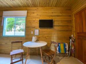 Habitación con mesa, sillas y TV. en Casa do Bosque, 500m da praia Campeche, en Florianópolis