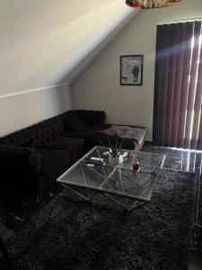 a living room with a black couch and a glass table at NEW GUEST HOUSE 13 in Maribor