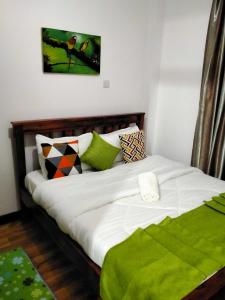 1 dormitorio con 1 cama con sábanas blancas y almohadas verdes en Two Bedrooms Furnished Apartment in Nakuru en Nakuru