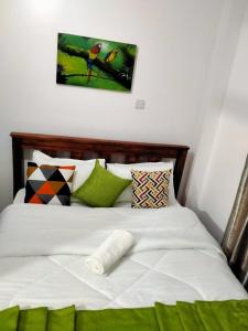 Una cama con almohadas verdes y blancas. en Two Bedrooms Furnished Apartment in Nakuru en Nakuru