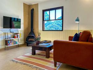 uma sala de estar com um sofá, uma mesa e uma lareira em Charmoso chale c WiFi e linda vista em Itaipava RJ em Petrópolis