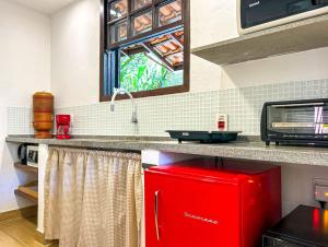 um frigorífico vermelho numa cozinha com uma janela em Charmoso chale c WiFi e linda vista em Itaipava RJ em Petrópolis