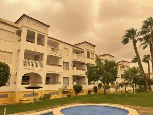 維拉馬丁的住宿－Villamartín PlazaGolf，一座白色的大建筑,前面设有一个游泳池