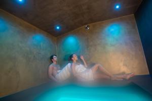 duas mulheres sentadas numa banheira num quarto com luzes em Hotel Weisses Rössl 3Sup em Laion