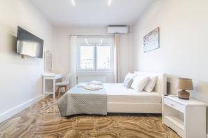 a white bedroom with a bed and a window at Studio for Couples near Beach in Gázion