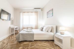 a white bedroom with a bed and a window at Studio for Couples near Beach in Gázion