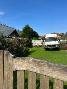 une camionnette garée dans une cour derrière une clôture en bois dans l'établissement Sympathique camping car J9, à Avesnelles
