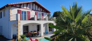 a white house with a balcony and a palm tree at Appartement Maeva in Saint-Pée-sur-Nivelle