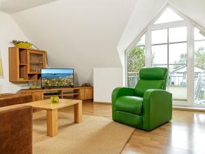 a living room with a green chair and a tv at Appartements Am Reiterhof Nixe in Timmendorf