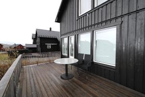 een houten terras met een tafel en stoelen op een gebouw bij RIBO Apartment Katterjåkk in Riksgränsen