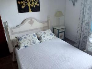 Un dormitorio con una cama blanca con almohadas. en FINCA EL ROMERO, Finca a 15 minutos de Sevilla, en Alcalá del Río