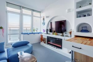a living room with a blue couch and a tv at Anna Maria Santorini - Greek Suite & Large sea terrace Arcadia in Odesa