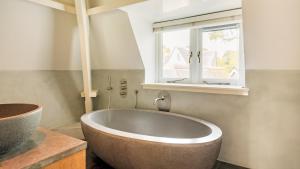 baño con bañera grande y ventana en Villa van Reenenpark, en Bergen 26 fotos más