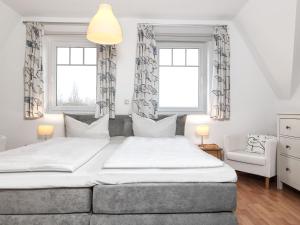 ein Schlafzimmer mit einem großen Bett und zwei Fenstern in der Unterkunft Reihenhäuser Timmendorf Strand Haus Strandmuschel in Insel Poel