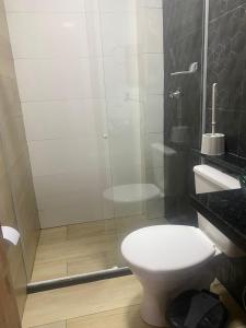 a bathroom with a toilet and a glass shower at Segunda Casa- Seu cantinho na Praia do Morro em Guarapari - Quartos suítes 2 até 4 pessoas in Guarapari