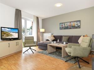 ein Wohnzimmer mit einem Sofa und einem TV in der Unterkunft Haus Südwester Austernperle in Timmendorf