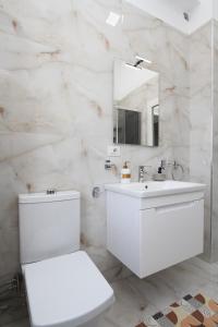 een witte badkamer met een toilet en een wastafel bij Cityscape Delight in Shkodër