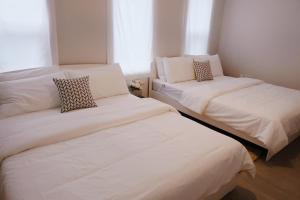 two beds in a room with white sheets and pillows at Blue Casa in Seogwipo