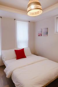 a bedroom with a large white bed with a red pillow at Blue Casa in Seogwipo