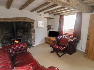 a living room with leather furniture and a stone fireplace at Brewers Cottage in Kings Nympton