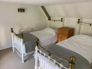 Kings NymptonにあるBrewers Cottageのベッドルーム1室(ツインベッド2台、木製ドレッサー付)