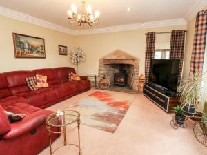 a living room with a red couch and a fireplace at Shore Hall in Littleborough