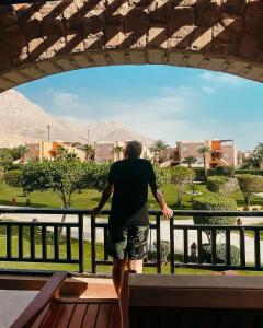 a man standing on a railing looking out at a city at Mövenpick Resort El Sokhna in Ain Sokhna