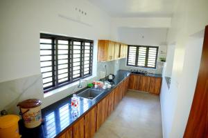 a large kitchen with wooden cabinets and a sink at Vaishnavam Double Bedroom Villa in Thekkady