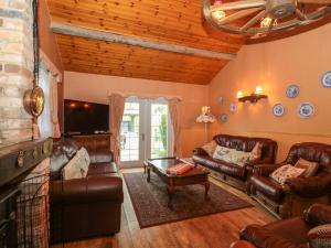 een woonkamer met lederen meubels en een stenen open haard bij Rose Cottage in Swanage