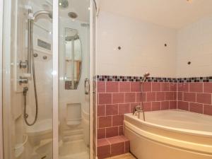 a bathroom with a tub and a shower with pink tiles at Rose Cottage in Swanage +23 photos