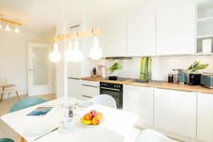 una cocina con armarios blancos y una mesa con un bol de fruta en Apartment "Sonnenlaune" en Garz-Usedom