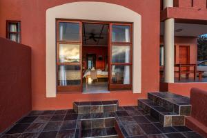 ein rotes Gebäude mit Glasfenstern und Steintreppen in der Unterkunft Island Cottage Guesthouse in Lüderitz