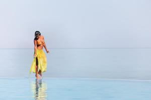 Una mujer con un vestido amarillo parada en el agua en Mövenpick Resort El Sokhna, en Ain Sokhna