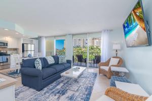 a living room with a blue couch and a kitchen at Renovated Condo Offering Free Beach Access!! in Marco Island