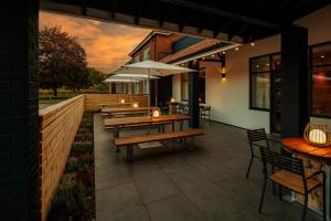 a patio with wooden tables and chairs and an umbrella at Holiday Inn High Wycombe M40, Jct.4 by IHG in High Wycombe
