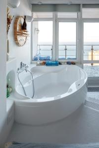 a white bath tub in a bathroom with windows at Anna Maria Santorini - Greek Suite & Large sea terrace Arcadia in Odesa