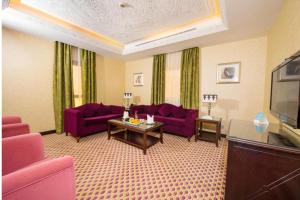 a living room with purple couches and a tv at Mercure Jeddah Al Hamraa Hotel in Jeddah