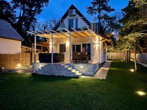 una casa blanca con luces en el césped en Felix House Siófok, en Siófok