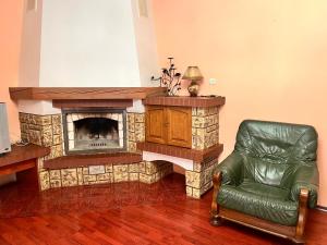 uma sala de estar com uma lareira de pedra e uma cadeira de couro em Mala Praha em Uzhhorod