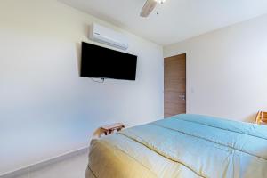 a bedroom with a bed and a tv on the wall at Rainbow Fish Hideaway @ TAO Santamar E201 in Akumal