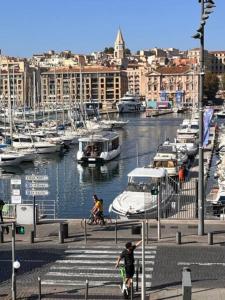 a man riding a bike near a marina with boats at T4 Marseille Vue imprenable sur Vieux Port in Marseille