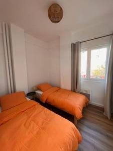 2 orangefarbene Betten in einem Zimmer mit Fenster in der Unterkunft T4 Marseille Vue imprenable sur Vieux Port in Marseille