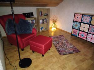 a living room with a red chair and a red stool at Zuhause in Hofs ,Leutkirch im Allgäu in Leutkirch im Allgäu