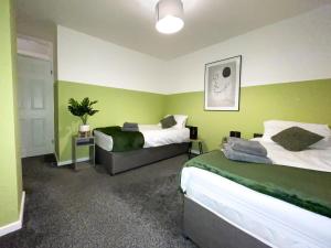 two beds in a room with green walls at Modern House with Fast WIFI & FREE Parking - Recently Refurbished - Contractor Friendly by IRWELL STAYS in Cronton