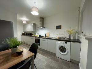 a kitchen with a washing machine and a table at Modern House with Fast WIFI & FREE Parking - Recently Refurbished - Contractor Friendly by IRWELL STAYS in Cronton