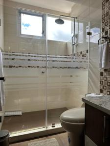baño con ducha, aseo y ventana en Instant Hotel - Villa Palermo Apartments, en Ambato