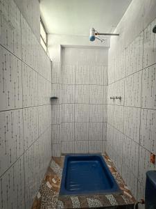 Baño de azulejos blancos con bañera azul en Hostal Sol y Lago en Copacabana