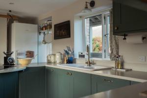 uma cozinha com armários verdes, um lavatório e uma janela em The Walled Garden em Totnes