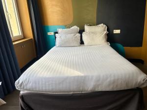1 cama con sábanas blancas y almohadas en una habitación en Appartement Censier Daubenton, en París