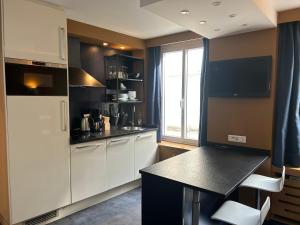 a kitchen with white cabinets and a black counter top at Appartement Censier Daubenton in Paris